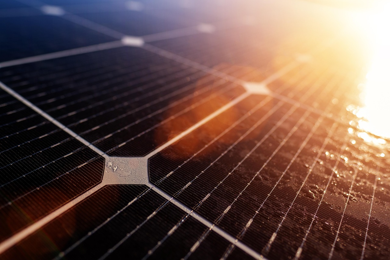 Close-up of a solar cell with metal contact lines and a sun flare